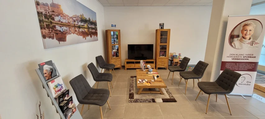 Moderner Wartebereich mit Sesseln, Tisch und Fernseher in einem hellen Raum.