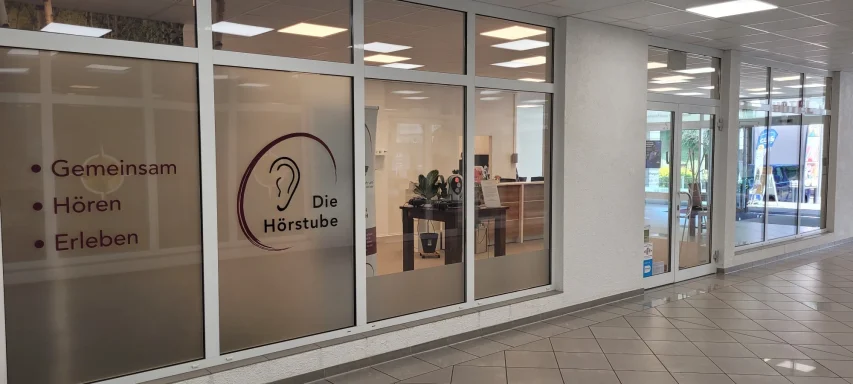 Büro mit großen Fenstern, Schriftzug und Pflanzen im Innenraum.