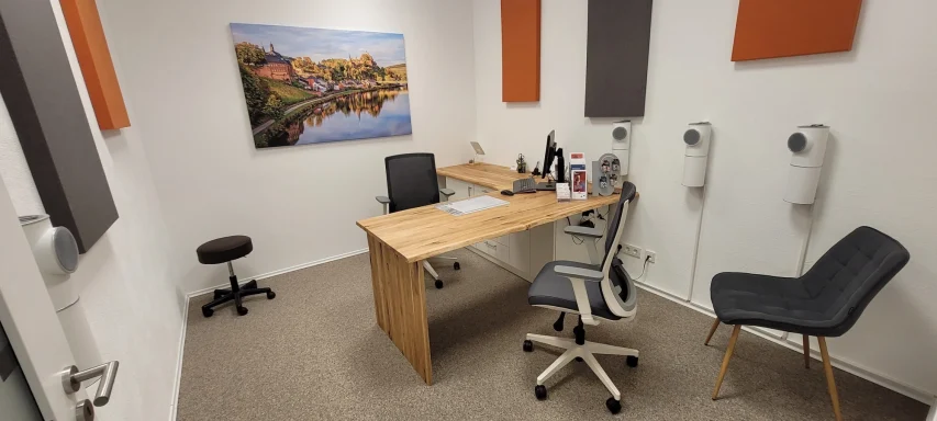 Büro mit Schreibtisch, Stuhl, Sitzgelegenheit und Bild von Saarburg an der Wand.